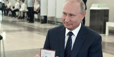 Wladimir Putin, Präsident von Russland, zeigt einer Mitarbeiterin der Wahlkommission seinen Pass in einem Wahllokal. Foto: Alexei Druzhinin/Pool Sputnik Kremlin/AP/dpa