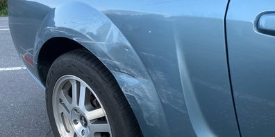 Beschädigungen am blauen Ford USA durch die Streifkollision. Der zweite Unfallfahrer mit eine Suzuki Jeep fuhr ohne Schadensregelung weiter.