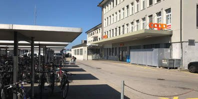 Bahnhofsnah: Die Rückseite des Coop ist nahe beim Bahngeleise und den abgestellten Fahrrädern_