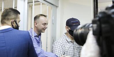 Iwan Safronow steht in einem Gerichtssaal in Moskau hinter Gittern und schüttelt einem Unterstützer die Hand. Foto: Sofia Sandurskaya/Moscow News Agency/AP/dpa