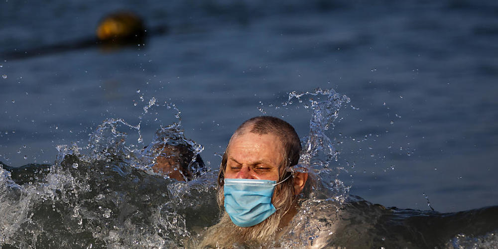 Ein Mann schwimmt mit Mundschutz an einem Strand in Tel Aviv. Foto: Oded Balilty/AP/dpa