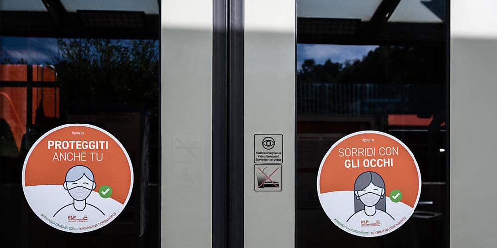 Hinweisschilder auf die Maskenpflicht an den Türen eines Lokalzugs der Lugano-Ponte-Tresa-Bahn FLP.