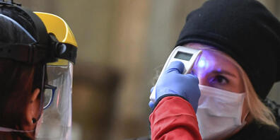 ARCHIV - Eine Mitarbeiterin des Roten Kreuzes überprüft auf dem Hauptbahnhof am Zugangsbereich für Zugabfahrten die Temperatur einer Frau. (zu dpa «Anstieg bei Corona-Zahlen: Italien prüft Zwangseinweisung von Kranken») Foto: Claudio Furlan/LaPres...