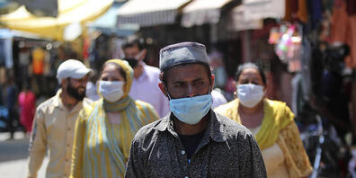 Passanten gehen mit Mundschutz über einen Markt in Jammu. Foto: Channi Anand/AP/dpa