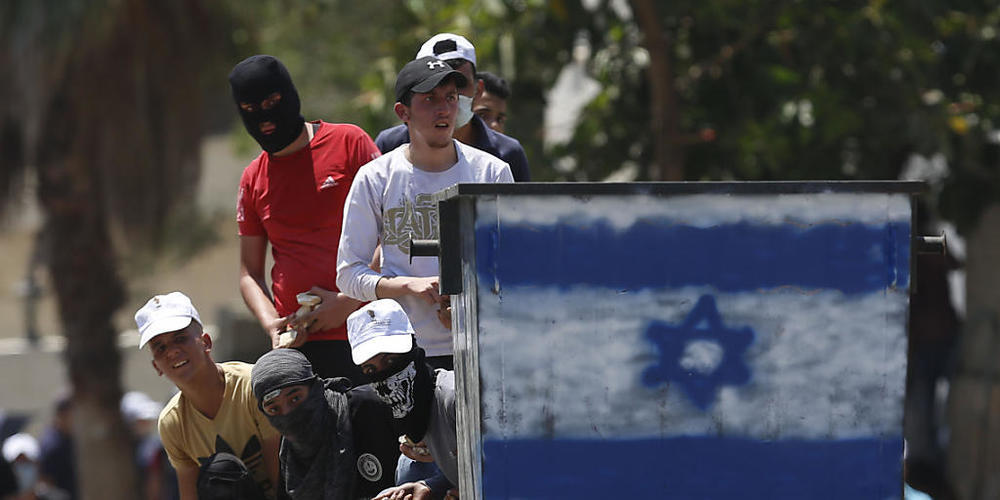 Palästinensische Demonstranten schleudern Steine auf israelische Truppen während eines Protests in Kufr Qaddum gegen Israels Plan, Teile des Westjordanlandes zu annektieren. Foto: Majdi Mohammed/AP/dpa