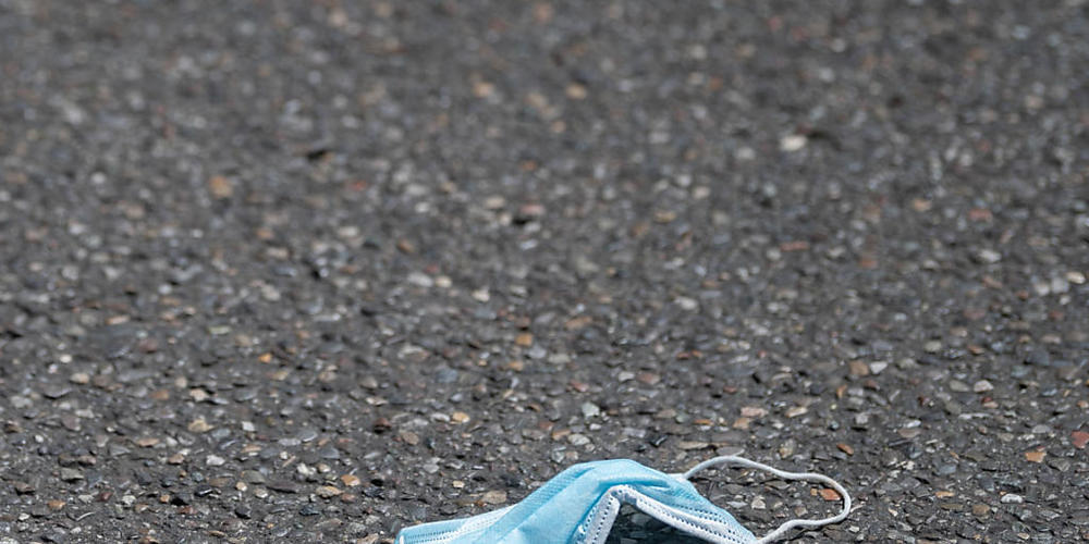 ARCHIV - Eine Mund-Nasenbedeckung liegt auf einer Straße. Foto: Marijan Murat/dpa
