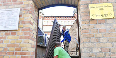 Tischlermeister Thomas Thiele hängt die Tür zum Grundstück der Synagoge aus. Foto: Hendrik Schmidt/dpa-Zentralbild/dpa