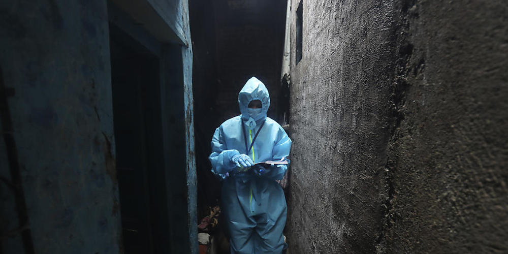 Ein Mitarbeiter des Gesundheitswesens geht in einem Slum, um bei den Bewohnern einen Corona-Test durchzuführen. Foto: Rafiq Maqbool/AP/dpa