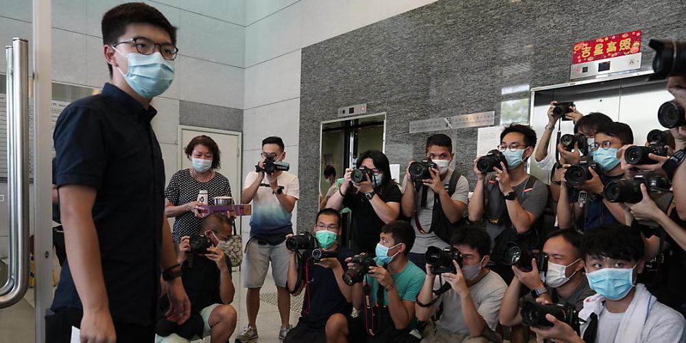 Der pro-demokratische Aktivist Joshua Wong (l) zeigt Journalisten die Nominierungsunterlagen, während er seine Kandidatur für die im September in Hongkong stattfindenden Wahlen zum Legislativrat einreicht. Foto: Vincent Yu/AP/dpa