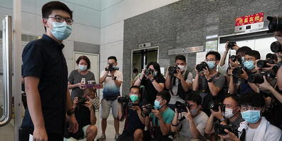Der pro-demokratische Aktivist Joshua Wong (l) zeigt Journalisten die Nominierungsunterlagen, während er seine Kandidatur für die im September in Hongkong stattfindenden Wahlen zum Legislativrat einreicht. Foto: Vincent Yu/AP/dpa