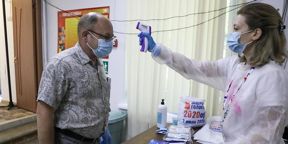 Eine medizinische Mitarbeiterin überprüft in Moskau überprüft die Körpertemperatur eines Mannes. Foto: Sofia Sandurskaya/AP/dpa