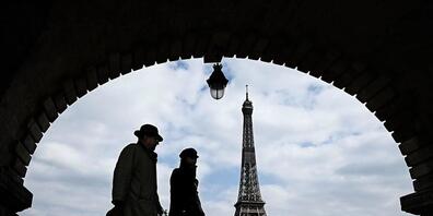 ARCHIV - Passanten gehen auf der Brücke «Pont de Bir-Hakeim», mit Blick auf den Eiffelturm. Foto: Philippe Lopez/AFP/dpa