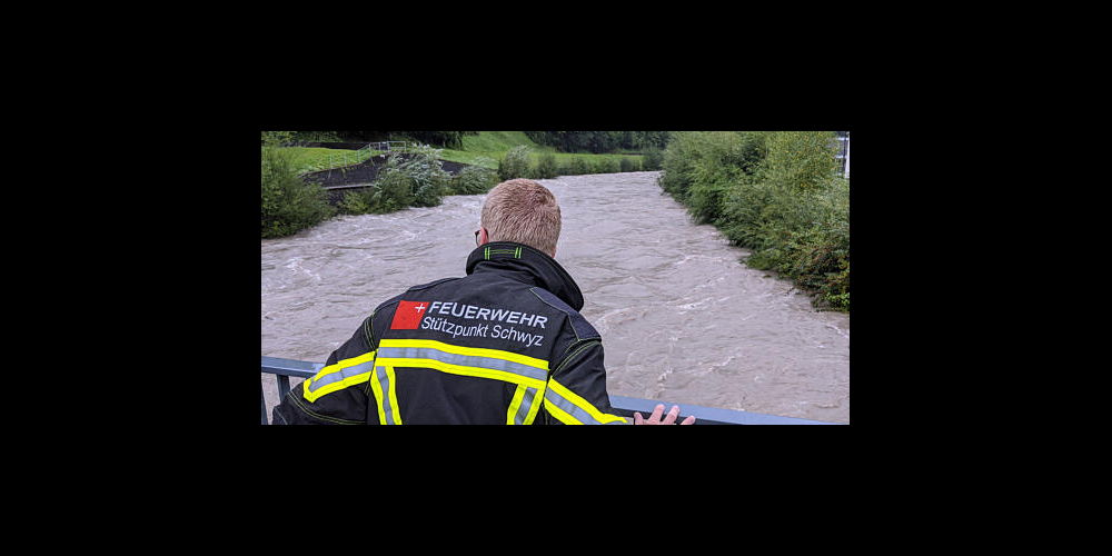 Das Pikett der Feuerwehr Stützpunkt Schwyz beobachtet in Ibach den Stand der Muota am frühen Sonntagnachmittag. (Bild: Geri Holdener)