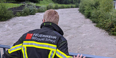 Das Pikett der Feuerwehr Stützpunkt Schwyz beobachtet in Ibach den Stand der Muota am frühen Sonntagnachmittag. (Bild: Geri Holdener)