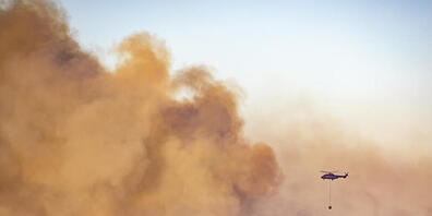 Ein Hubschrauber über den Rauchschwaden eines  Waldbrandes in der Gemeinde Almonaster la Real. Foto: A. Perez/Europa Press/AP/dpa
