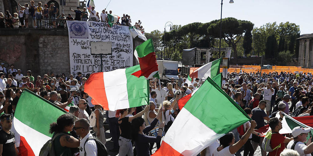 Teilnehmer einer Demonstration gegen die staatliche Corona-Politik schwenken italienische Nationalflaggen. Foto: Gregorio Borgia/AP/dpa