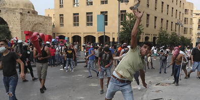 Demonstranten werfen bei einem regierungskritischen Protest in der Nähe des Parlamentsplatzes in Beirut Steine in Richtung der Bereitschaftspolizei. Foto: Bilal Hussein/AP/dpa