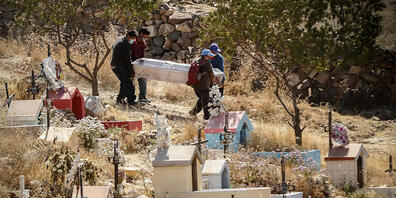 ARCHIV - Menschen mit Mundschutzmasken tragen inmitten der Corona-Pandemie einen Sarg bei einre Beerdigung auf dem Friedhof El Cebollar in Peru. Foto: Denis Mayhua/dpa