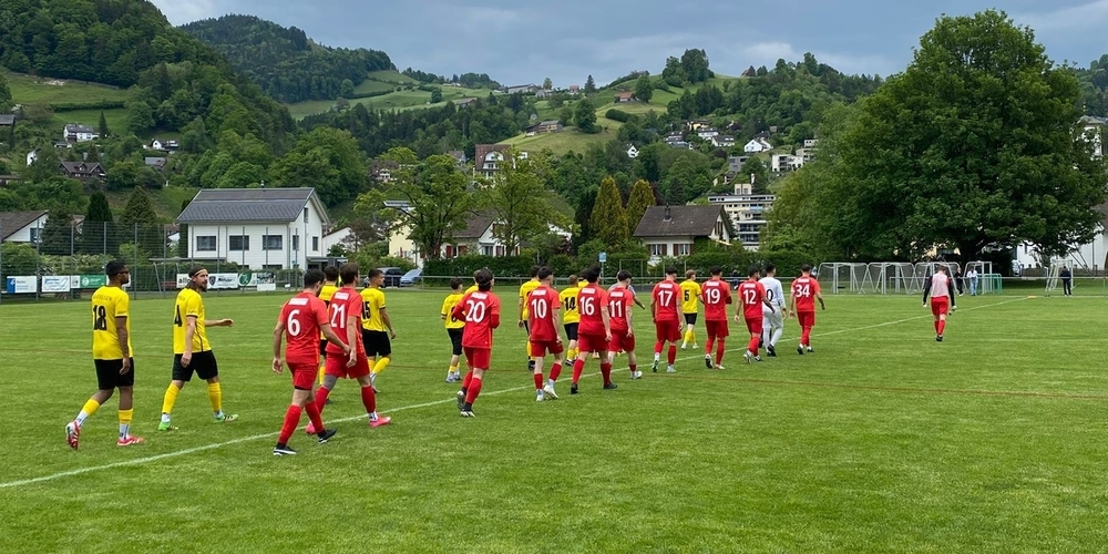 Die Spieler des FC Uznach (ganz rot) und des FC Wattwil Bunt 1929 (gelb-schwarz) beim Einlaufen auf dem Sportplatz Grüenau.