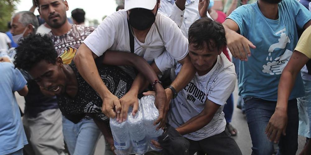 dpatopbilder - Migranten ringen um Wasserflaschen. Foto: Petros Giannakouris/AP/dpa