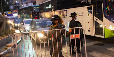 dpatopbilder - Ein israelischer Grenzpolizist errichtet in der ultra-orthodoxen jüdischen Stadt Bnei Brak vor einer nächtlichen Ausgangssperre auf einer Hauptstraße eine Absperrung. Foto: Oded Balilty/AP/dpa