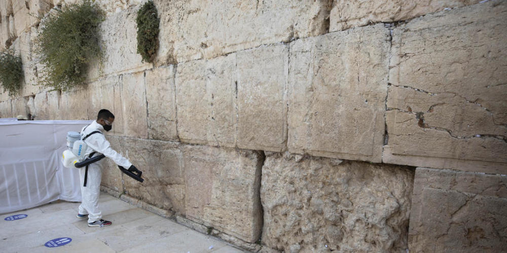 dpatopbilder - Ein Arbeiter verteilt Desinfektionsmittel als Vorsichtsmaßnahme gegen das Coronavirus an der Klagemauer, der heiligsten Stätte, an der Juden in Jerusalem beten können. Foto: Sebastian Scheiner/AP/dpa