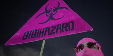 Ein Demonstrant hält ein Schild gegen den israelischen Premierminister Netanjahu und die landesweite Coronavirus-Sperre. Foto: Ariel Schalit/AP/dpa