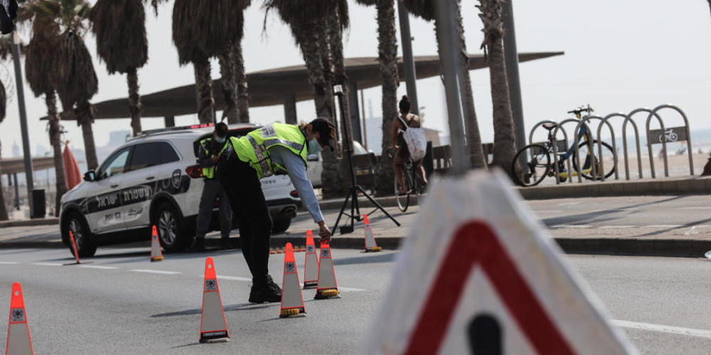Polizeibeamte mit Mund-Nase-Schutz sperren eine Straße ab. Die israelische Regierung will mit einem zweiten landesweiten Lockdown eine weitere Ausbreitung des Coronavirus verhindern. Foto: Ilia Yefimovich/dpa