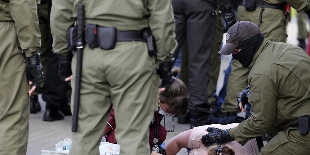 Eine Notärztin kümmert sich am Rande einer Demonstration gegen die Wahlergebnisse in Belarus um eine verletzte Frau, die neben Polizeibeamten auf dem Boden liegt. Foto: Uncredited/TUT.by/dpa