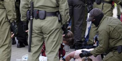Eine Notärztin kümmert sich am Rande einer Demonstration gegen die Wahlergebnisse in Belarus um eine verletzte Frau, die neben Polizeibeamten auf dem Boden liegt. Foto: Uncredited/TUT.by/dpa
