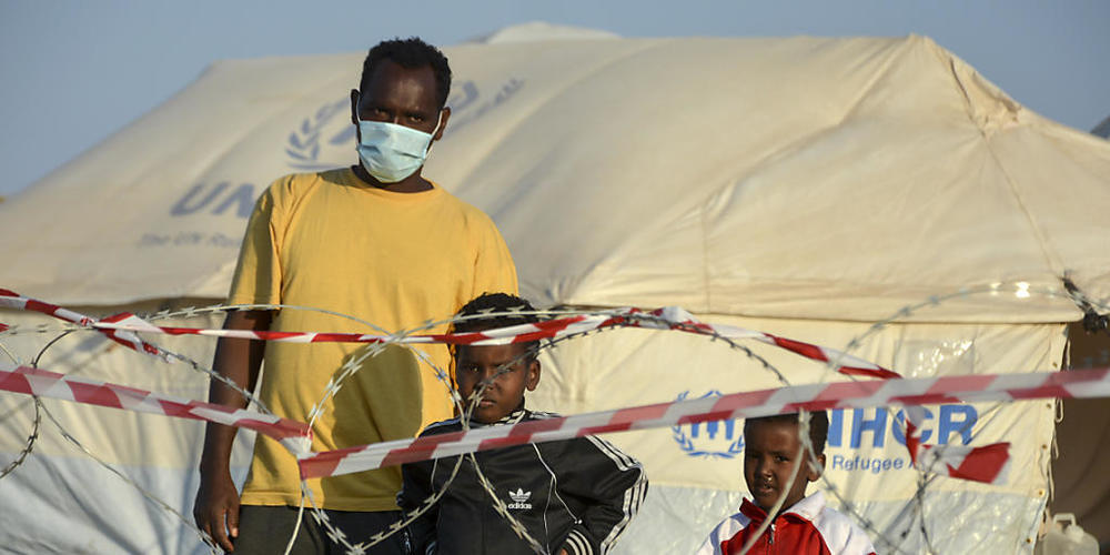 Ein Migrant steht mit zwei Kindern vor einem Stacheldrahtzaun im neu errichteten temporären Flüchtlingslager in Kara Tepe. Foto: Panagiotis Balaskas/AP/dpa