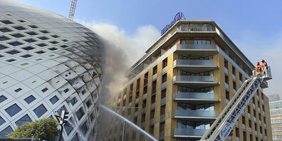 Feuerwehrleute löschen einen Brand im Geschäftsviertel der libanesischen Hauptstadt. Betroffen ist das sich noch im Bau befindlichen Gebäude (l), das von der Architektin Zaha Hadid entworfen wurde. Foto: Fadi Tawil/AP/dpa