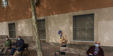 Ältere Menschen sitzen in einem Park in Vallecas, einem ärmeren Madrider Viertel, das teilweise abgeriegelt ist. Foto: Bernat Armangue/AP/dpa