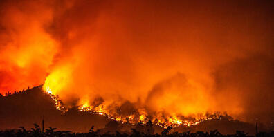 Von den bewaldeten Hügeln in der Nähe von Calistoga nahe von Weinreben schlagen Flammen des "Glass"-Feuers empor. Foto: Imagespace/ZUMA Wire/dpa