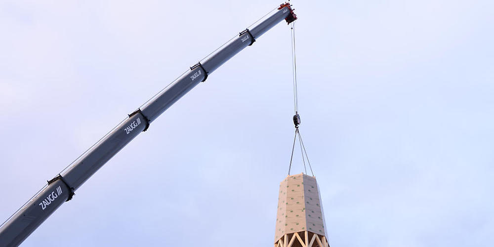 Der erste Teil der Turmspitze wird mit einem Autokran auf den Kirchturm in Herzogenbuchsee montiert. Der Kirchturm war an Heiligabend 2019 durch einen Brand zerstört worden.