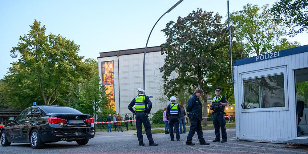 dpatopbilder - Mehrere Polizeibeamte und Zivilisten stehen im abgesperrten Bereich vor der Synagoge in Hamburg-Harvestehude. Foto: Jonas Walzberg/dpa