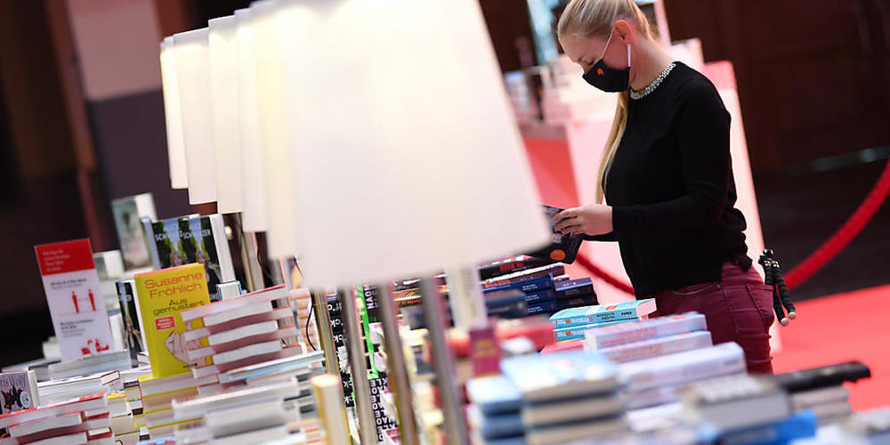 Eine Mitarbeiterin der Frankfurter Buchmesse steht vor der Eröffnungspressekonferenz der Frankfurter Buchmesse an einem Buchstand in der Festhalle. Foto: Arne Dedert/dpa pool/dpa