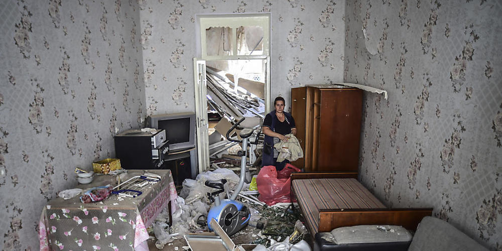 Eine Frau steht in ihrem beschädigten Haus, welches durch Beschuss durch armenische Soldaten beschädigt wurde. Foto: Ismail Coskun/AP/IHA/dpa