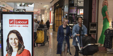 Menschen gehen in einem Einkaufszentrum an einer elektronischen Plakatwand vorbei, die ein Foto der neuseeländischen Premierministerin Jacinda Ardern zeigt. Neuseeländer gehen bei den Parlamentswahlen am Samstag, den 17.10.2020, an die Urnen. Foto...