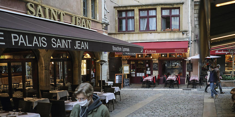 ARCHIV - Ein Mann trägt eine Maske und geht an den leeren Tischen und Stühlen von Restaurants vorbei. Die Corona-Pandemie hat in den fünf größten Volkswirtschaften Europas das Verbrauchervertrauen nachhaltig erschüttert. Foto: Laurent Cipriani/AP/dpa