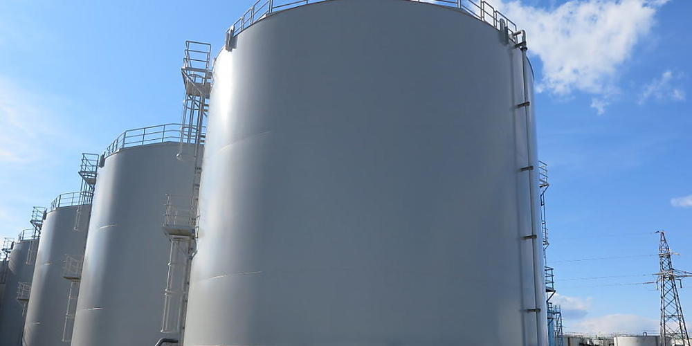 ARCHIV - Mitarbeiter des Betreiberkonzerns Tepco stehen vor riesigen Tanks, in denen verstrahltes Wasser, das bei der andauernden Kühlung der beschädigten Reaktoren von Fukushima anfällt, gelagert wird. Inzwischen haben sich 1,1 Millionen Tonnen a...