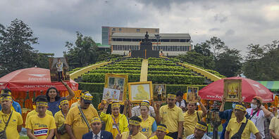 Demonstranten tragen gelbe Kleidung und halten Abbildungen des thailändischen Königs Maha und der Königin Suthida bei einem Protest vor der Ramkhamhaeng Universität, um ihre Loyalität für die Institution unter Beweis zu stellen. Foto: Peerayot Lak...