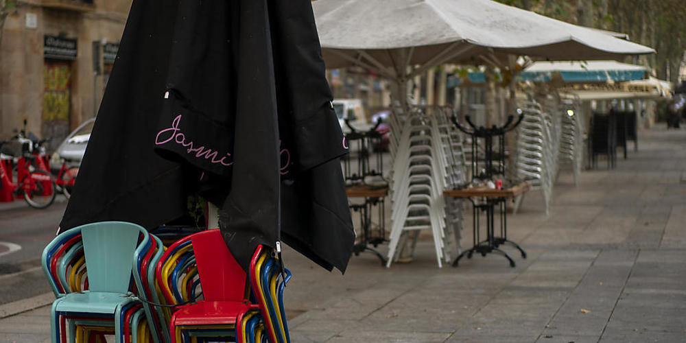 Stühle und Tische stapeln sich auf einer Bar-Terrasse in Barcelona. Foto: Emilio Morenatti/AP/dpa