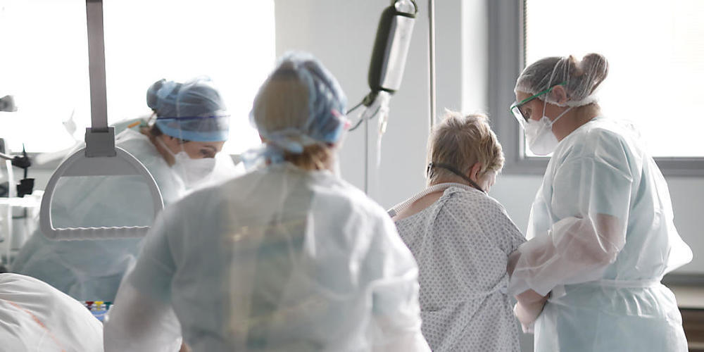 Medizinisches Personal hilft einem Corona-Patienten im Nouvel Hopital Civil. Foto: Jean-Francois Badias/AP/dpa