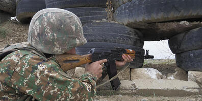 Ein armenischer Soldat zielt in Richtung der aserbaidschanischen Stellungen. Foto: -/AP/dpa