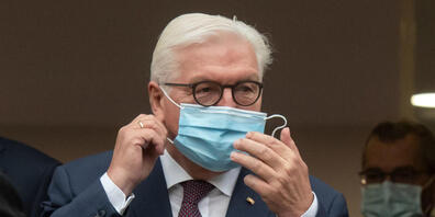 ARCHIV - Bundespräsident Frank-Walter Steinmeier steht vor einem Gebäude der Uniklinik und nimmt für ein Gruppenfoto seine Maske ab. Foto: Bernd Thissen/dpa