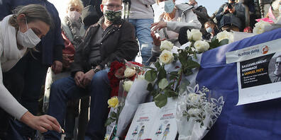Eine Frau zündet eine Kerze für den ermordeten Lehrer Samuel Paty an. Foto: Michel Euler/AP/dpa