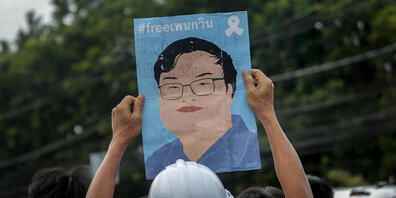 Ein Demonstrant in Bangkok zeigt ein Plakat mit einem Bild des kürzlich inhaftierten Protestführers Parit Chiwarak. Foto: Sakchai Lalit/AP/dpa