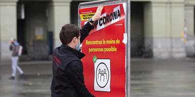 Coronavirus: Ein neues rotes BAG-Plakat mit der Verhaltensregel "Treffen Sie so wenige Menschen wie möglich"wird auf dem Bundesplatz in Bern installiert.