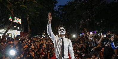 Ein pro-demokratischer Demonstrant hält bei einer Protestaktion, die wie eine Modenschau aussieht, seine Finger zum symbolischen Drei-Finger-Gruß des Widerstands in die Höhe. Die Demonstrierenden fordern weiterhin den Rücktritt von Ministerpräside...